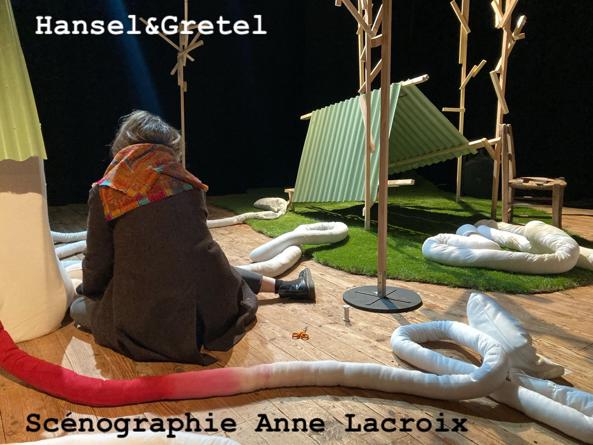 Une actrice assise sur scène au milieu du décor